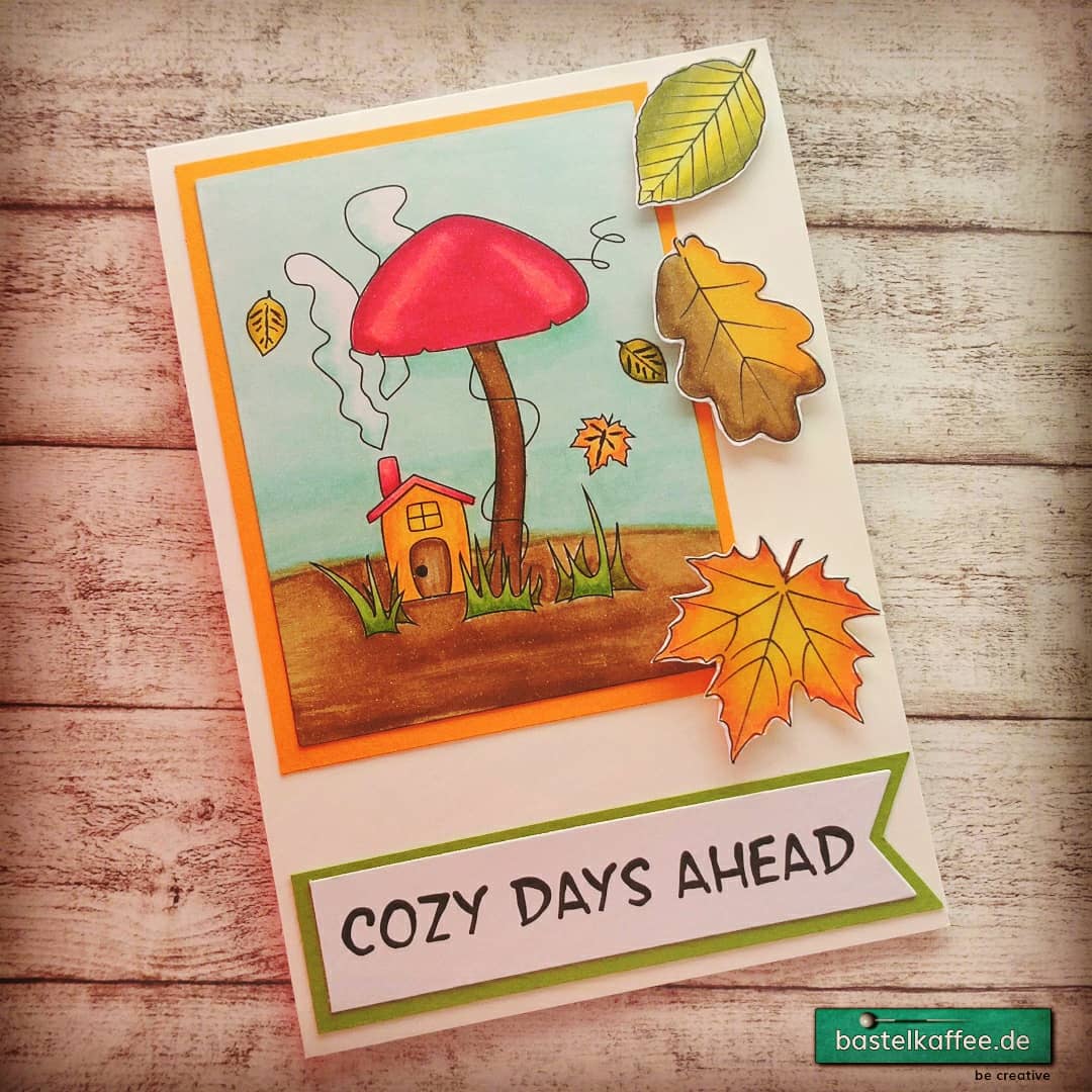 DIY Grußkarte mit coloriertem Herbsmotiv. RauchendesHäuschen unter einem Pilz. Fallende Blätter. Text: Cozy Days Ahead.